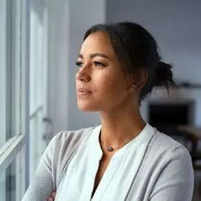 Woman gazing thoughtfully out a window.