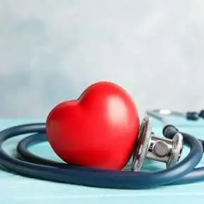 Red heart with stethoscope on table.