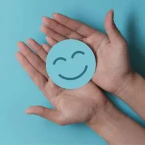 Hands holding a blue smiling face.