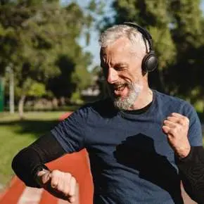 Man jogging with headphones on sunny day.